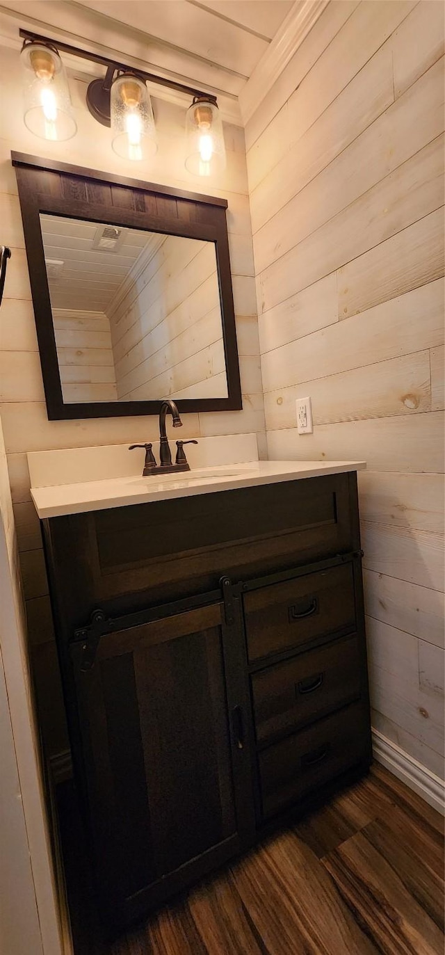 bathroom with hardwood / wood-style flooring, vanity, and wooden walls