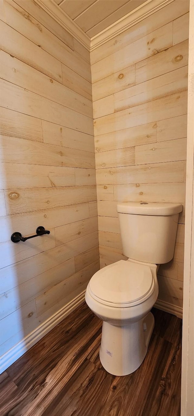 bathroom featuring wood-type flooring, toilet, and wooden walls