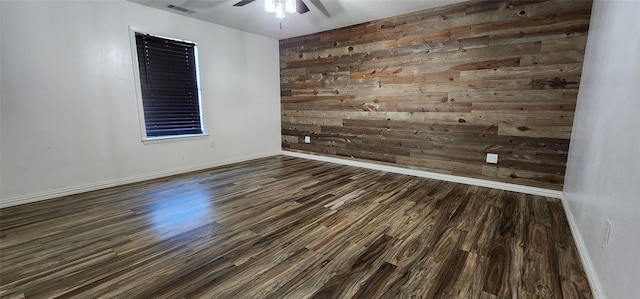 unfurnished room featuring ceiling fan, wood walls, and dark hardwood / wood-style flooring