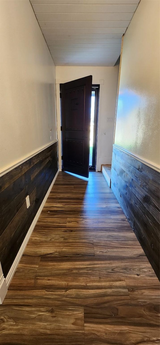 foyer entrance featuring wooden walls, dark hardwood / wood-style flooring, and vaulted ceiling