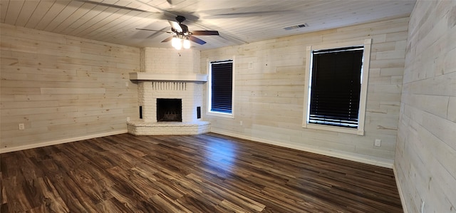 unfurnished living room with wooden walls, dark hardwood / wood-style floors, ceiling fan, a fireplace, and wood ceiling