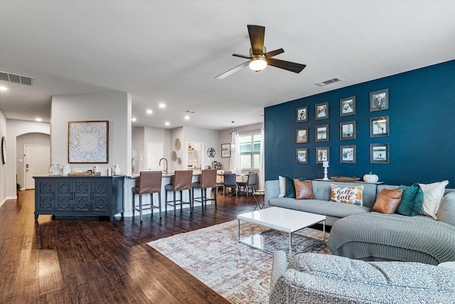 living room featuring dark wood-type flooring, sink, and ceiling fan