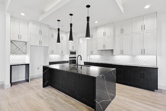 kitchen with a center island with sink, white cabinets, sink, and stainless steel appliances