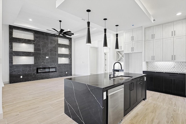 kitchen with sink, pendant lighting, dishwasher, white cabinetry, and an island with sink