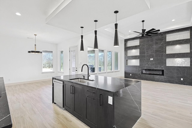 kitchen with pendant lighting, sink, an island with sink, stainless steel dishwasher, and a raised ceiling