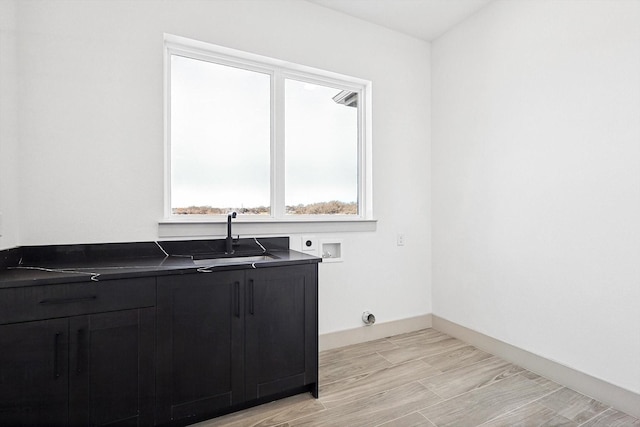 laundry area with sink, washer hookup, cabinets, hookup for an electric dryer, and light hardwood / wood-style flooring