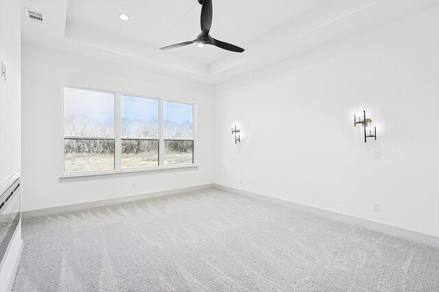 carpeted empty room featuring a tray ceiling and ceiling fan