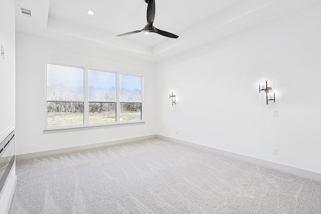 carpeted spare room featuring ceiling fan and a tray ceiling