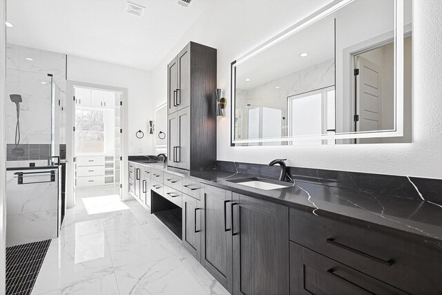 bathroom with a tile shower and vanity