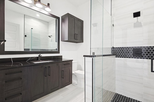 bathroom featuring vanity, toilet, and a shower with door