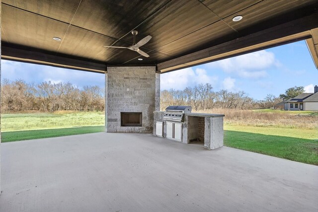 view of patio with an outdoor stone fireplace, ceiling fan, exterior kitchen, and grilling area