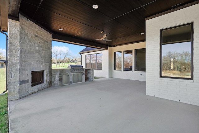 view of patio / terrace featuring an outdoor stone fireplace, a grill, ceiling fan, and an outdoor kitchen