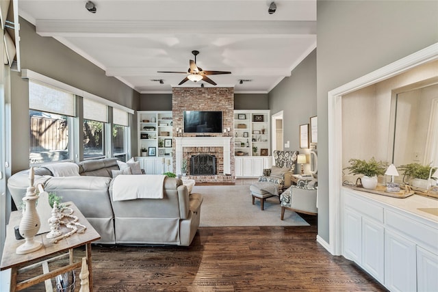 living room with crown molding, ceiling fan, dark hardwood / wood-style floors, a fireplace, and beamed ceiling