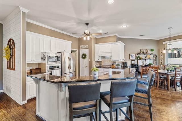 kitchen featuring stainless steel appliances, decorative light fixtures, a kitchen island, and white cabinets