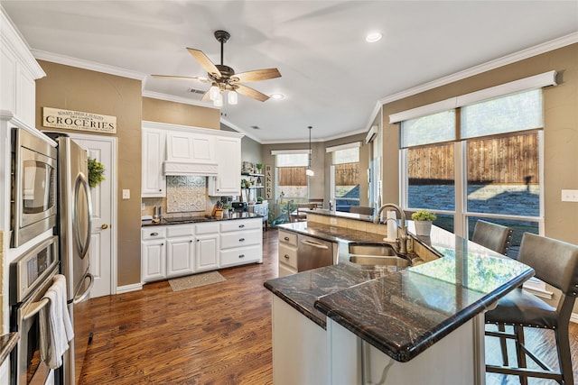 kitchen featuring stainless steel appliances, sink, white cabinets, and a kitchen bar