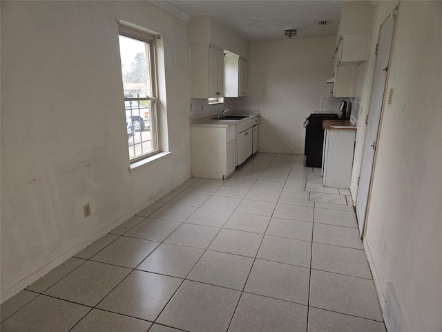 kitchen with white cabinetry, sink, light tile patterned flooring, and range