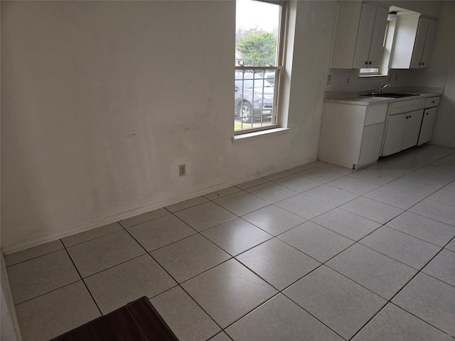 kitchen featuring light tile patterned floors, white cabinetry, and sink