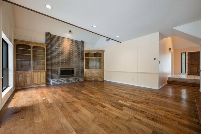 unfurnished living room featuring wood-type flooring, a fireplace, and vaulted ceiling