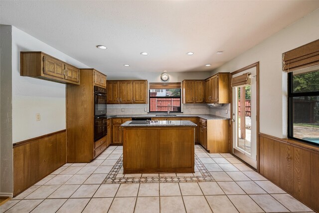 kitchen with light tile patterned floors, a center island, double oven, and backsplash