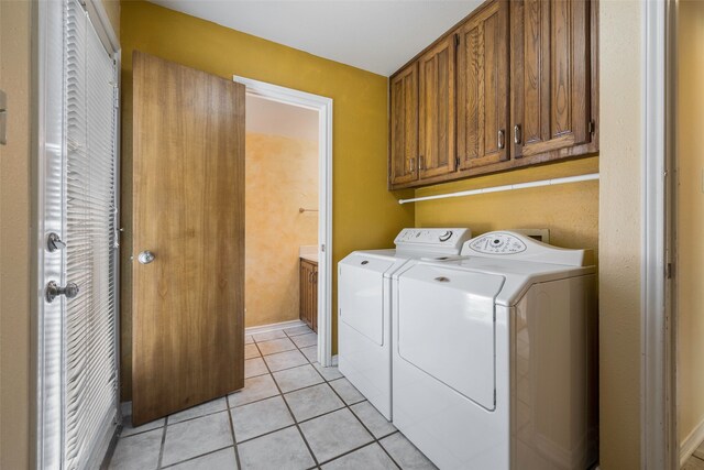 clothes washing area with washer and clothes dryer, cabinets, and light tile patterned floors