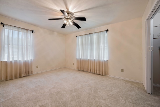 spare room with light colored carpet, plenty of natural light, and ceiling fan