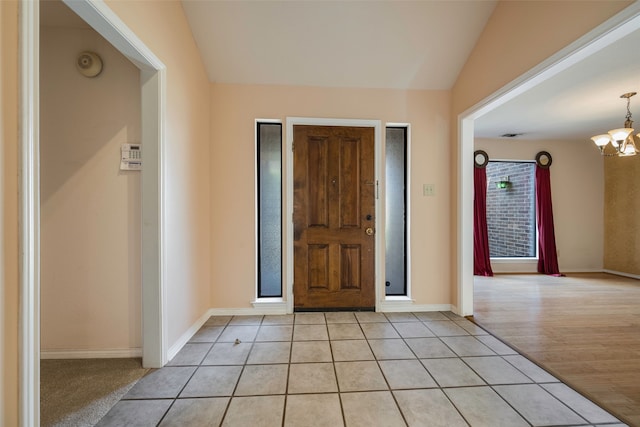 foyer featuring a chandelier, light tile patterned floors, and vaulted ceiling