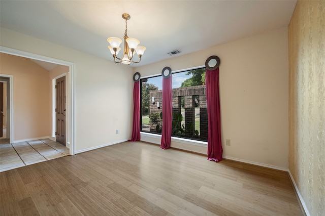 unfurnished room with a chandelier and light hardwood / wood-style floors