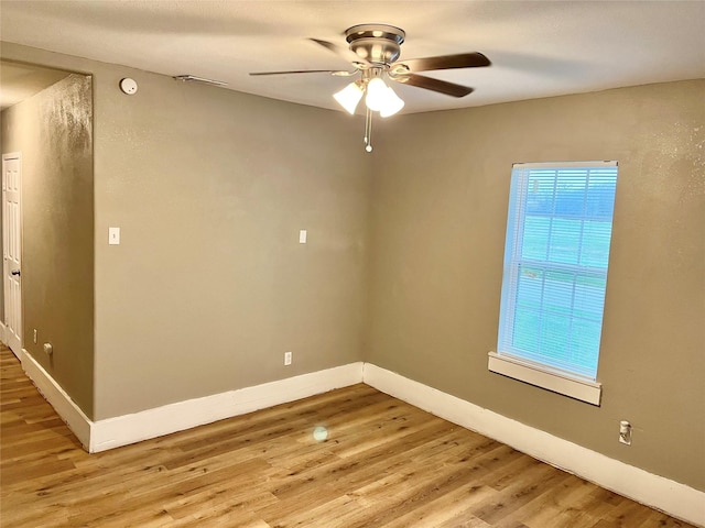 empty room featuring a wealth of natural light, ceiling fan, and light hardwood / wood-style floors