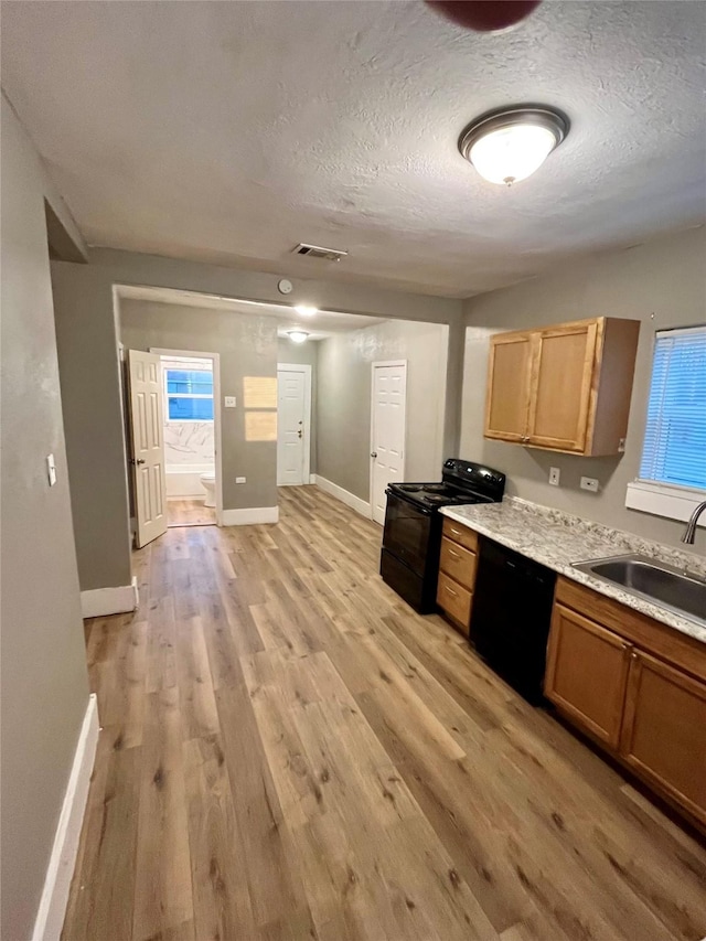 kitchen featuring sink, black appliances, a textured ceiling, and light wood-type flooring