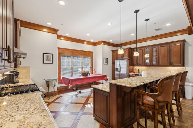 kitchen with stainless steel refrigerator with ice dispenser, pendant lighting, backsplash, and light stone counters