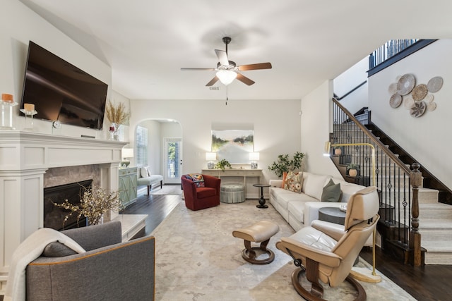 living room featuring a premium fireplace, wood-type flooring, and ceiling fan