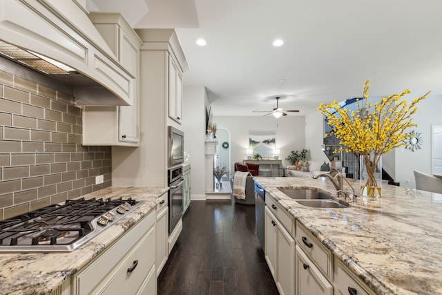 kitchen with premium range hood, sink, light stone counters, dark hardwood / wood-style flooring, and stainless steel appliances