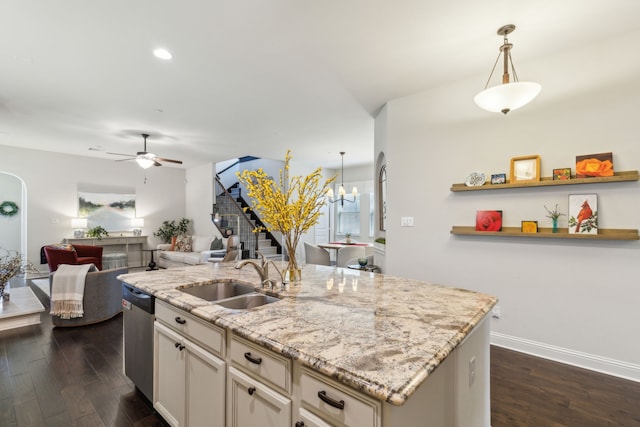 kitchen with pendant lighting, sink, dishwasher, a kitchen island with sink, and light stone countertops