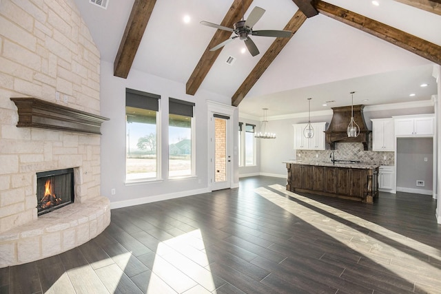 unfurnished living room with high vaulted ceiling, a stone fireplace, sink, ceiling fan, and beamed ceiling