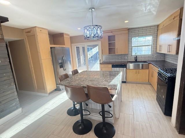 kitchen featuring sink, light brown cabinets, tasteful backsplash, hanging light fixtures, and appliances with stainless steel finishes