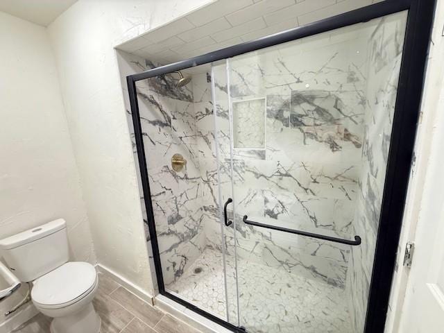 bathroom featuring a shower with shower door and toilet