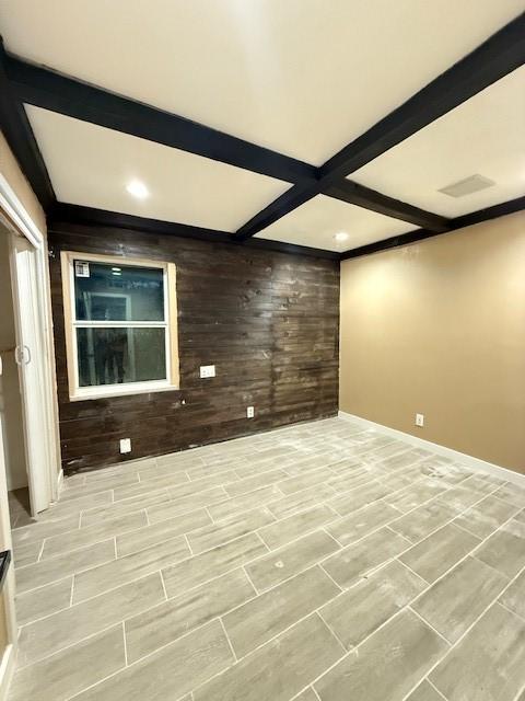 empty room with wood walls and beamed ceiling