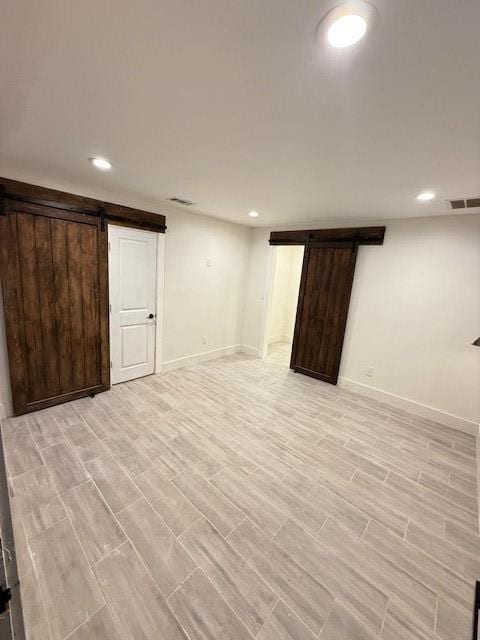 basement with light wood-type flooring and a barn door