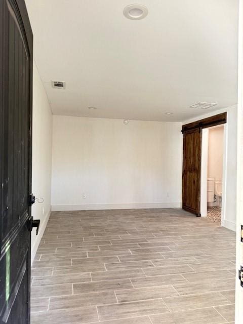 empty room with a barn door and light hardwood / wood-style flooring