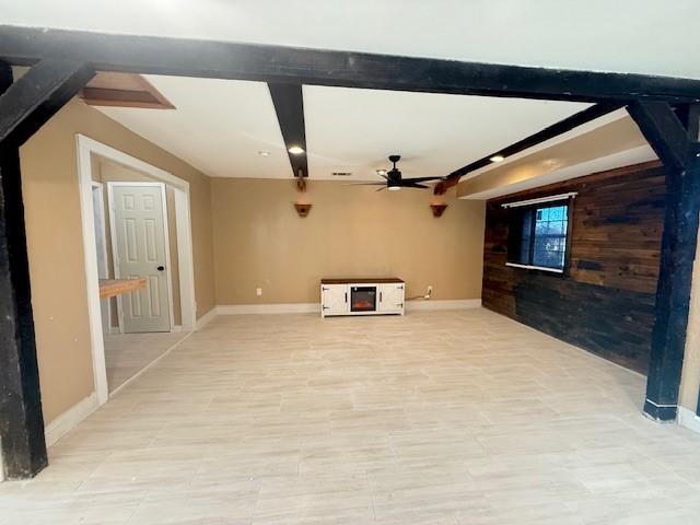 unfurnished living room with ceiling fan and beamed ceiling