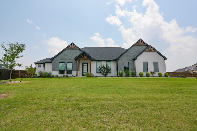 view of front of house with stone siding, fence, and a front yard