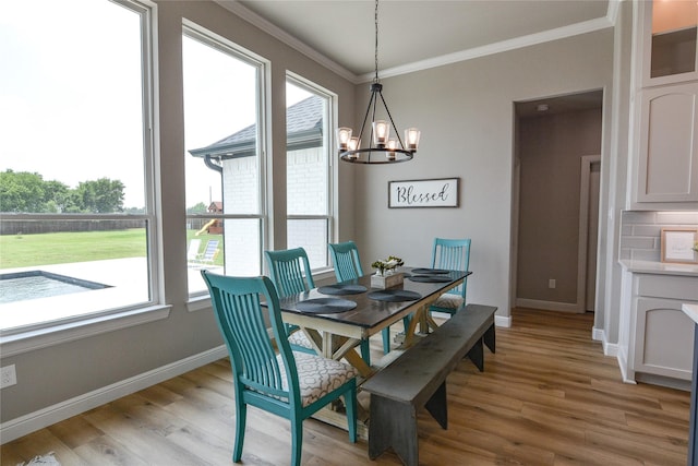 dining area featuring an inviting chandelier, ornamental molding, and light hardwood / wood-style floors