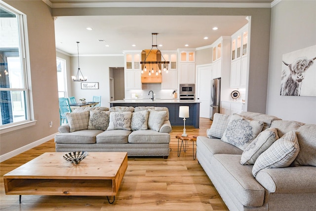 living room with a chandelier, recessed lighting, baseboards, light wood-type flooring, and crown molding