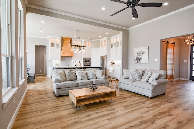 living area with ornamental molding, light wood-type flooring, baseboards, and a barn door