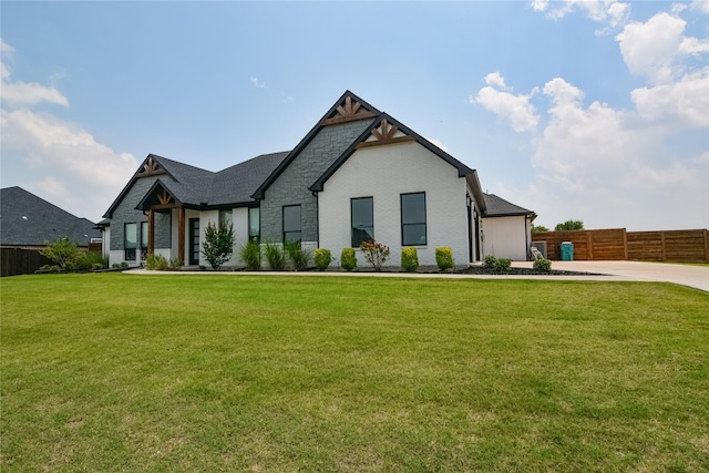 view of front facade featuring stone siding, a front lawn, fence, and brick siding