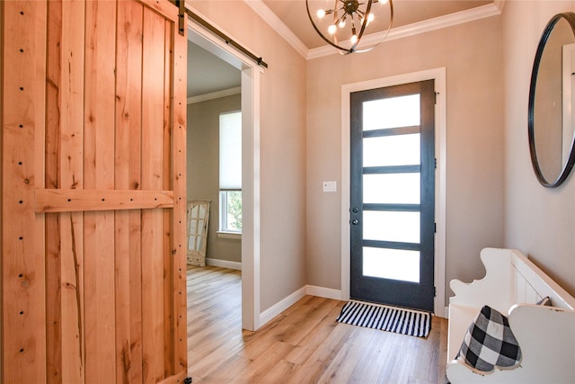 entryway with crown molding, light wood finished floors, a barn door, a chandelier, and baseboards