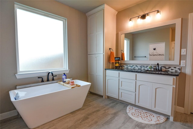 full bathroom featuring a freestanding bath, wood finished floors, vanity, and baseboards