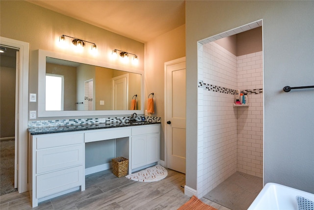 bathroom with a tile shower, vanity, and wood finished floors