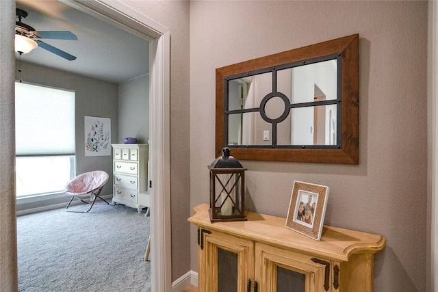 hall with carpet, baseboards, and a textured wall