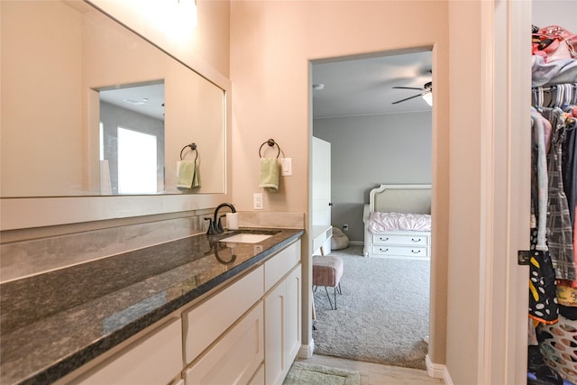 bathroom featuring a spacious closet, a ceiling fan, and vanity